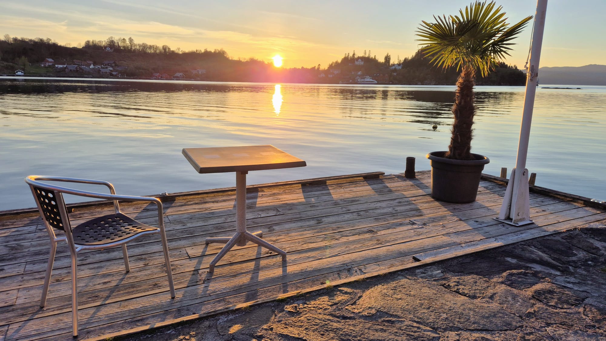 Stol, bord og palme ved sjøen i solnedgang hos Furrehytter