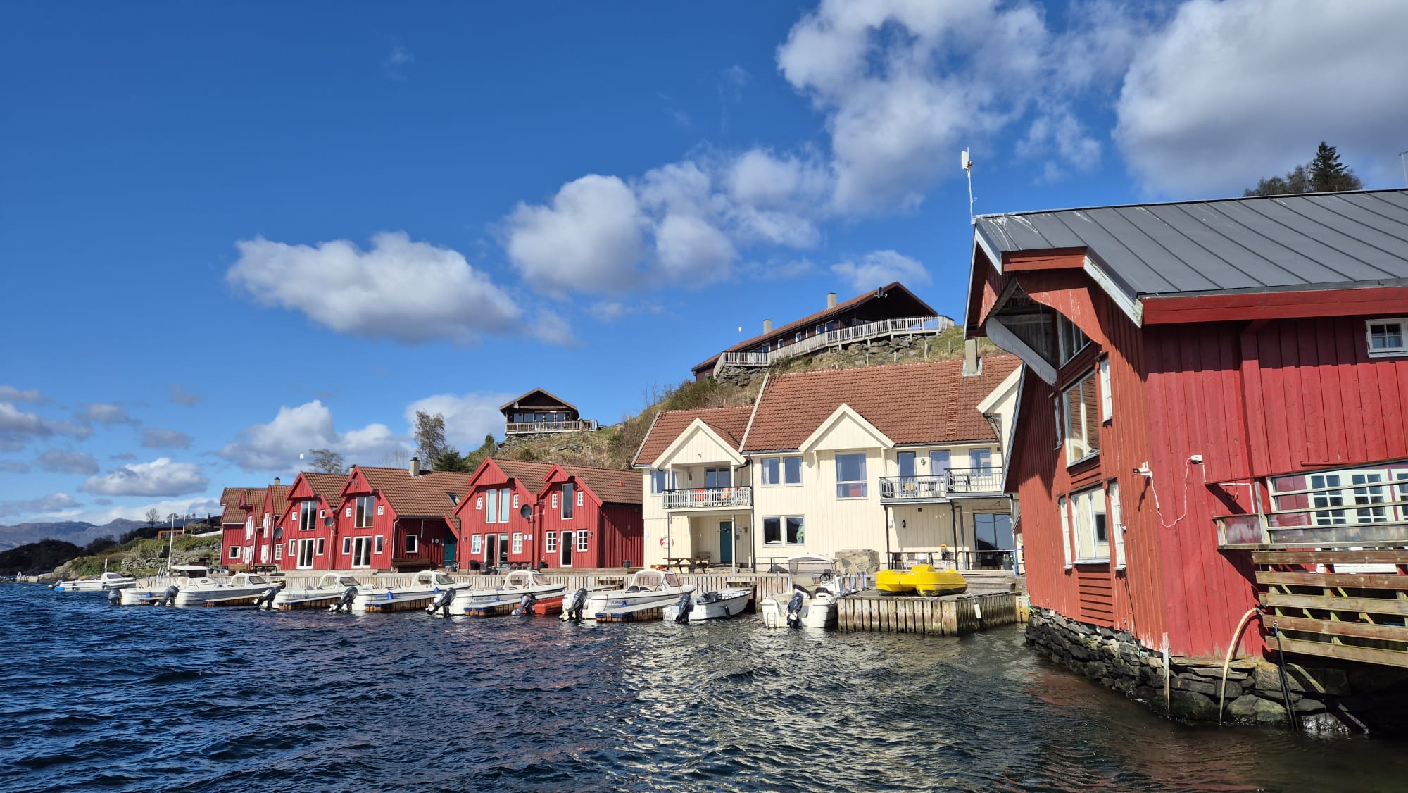 Hytter, leiligheter og utleiebåter langs brygga hos Furrehytter, sett fra sjøen